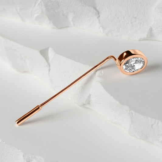 Rose gold lapel pin featuring an oval-cut lab-grown diamond, elegantly displayed on a textured white surface with layered details.